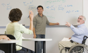 University professor with Muscular Dystrophy teaching students in a classroom.