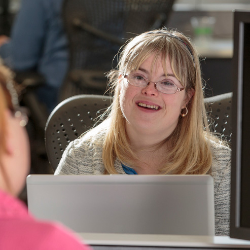 Young woman with Down Syndrome working at her computer in an office.