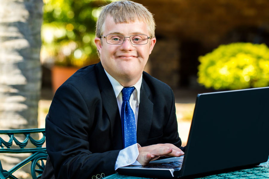 Young man with a developmental disability working at a laptop.