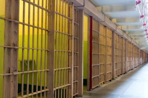 Prison cell row with bars closed and one open cell.