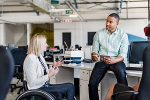 Businesswoman in a wheelchair sharing ideas with a coworker.